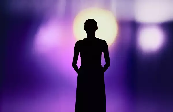 A silhouette of a person against a background with bright purple light
