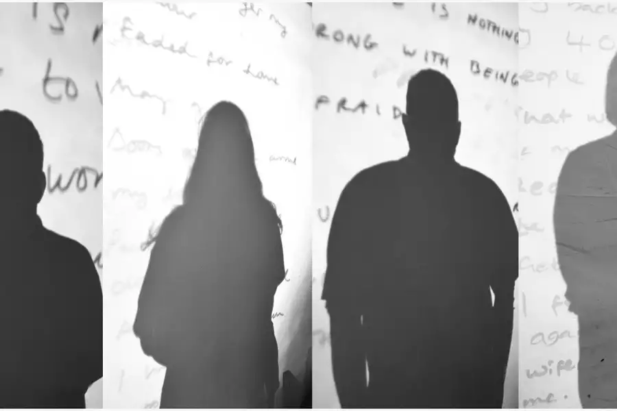 Silhouettes of four people cast on a wall with handwritten text in the background.