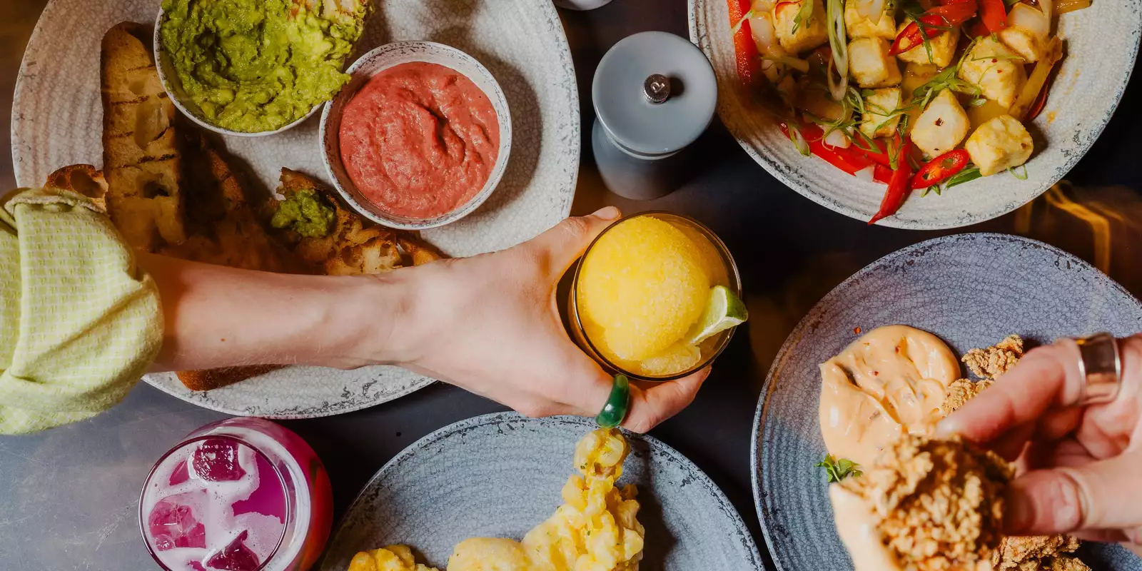 Three people pick small plates with Thai street food