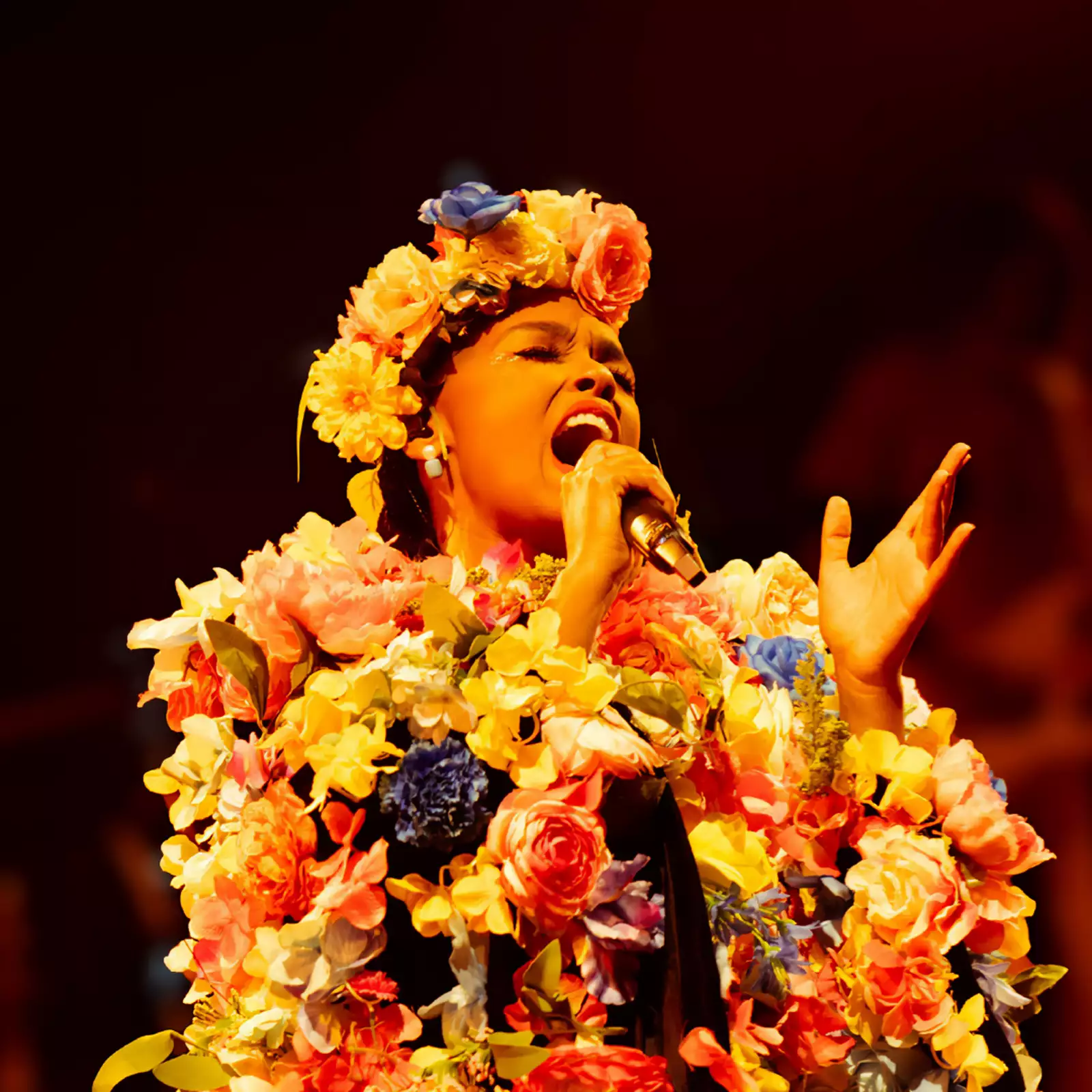 Janelle Monae sings while wearing a flower crown and flower embroidered jacket