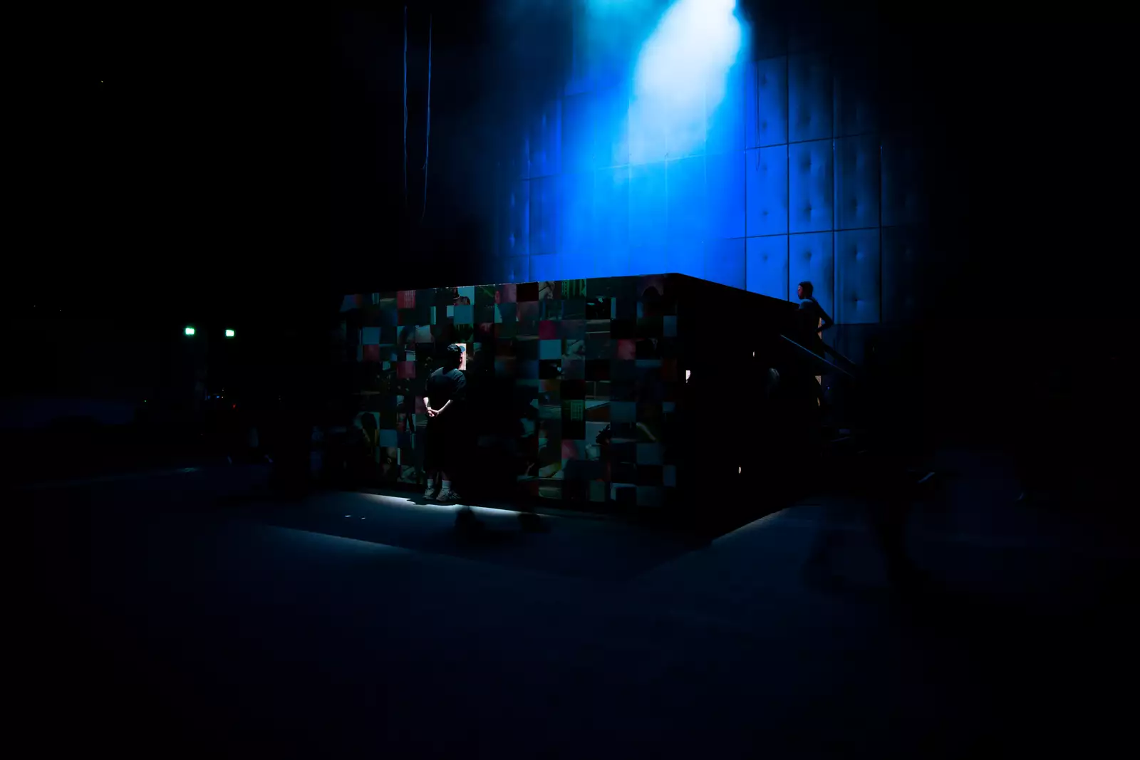 Audience members peering inside a large crate decorated with photographs, which 54: Manchester are performing inside