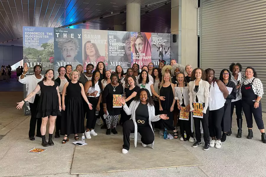 Group photo of NIA Choir, wearing black and white and smiling outside of Aviva Studios