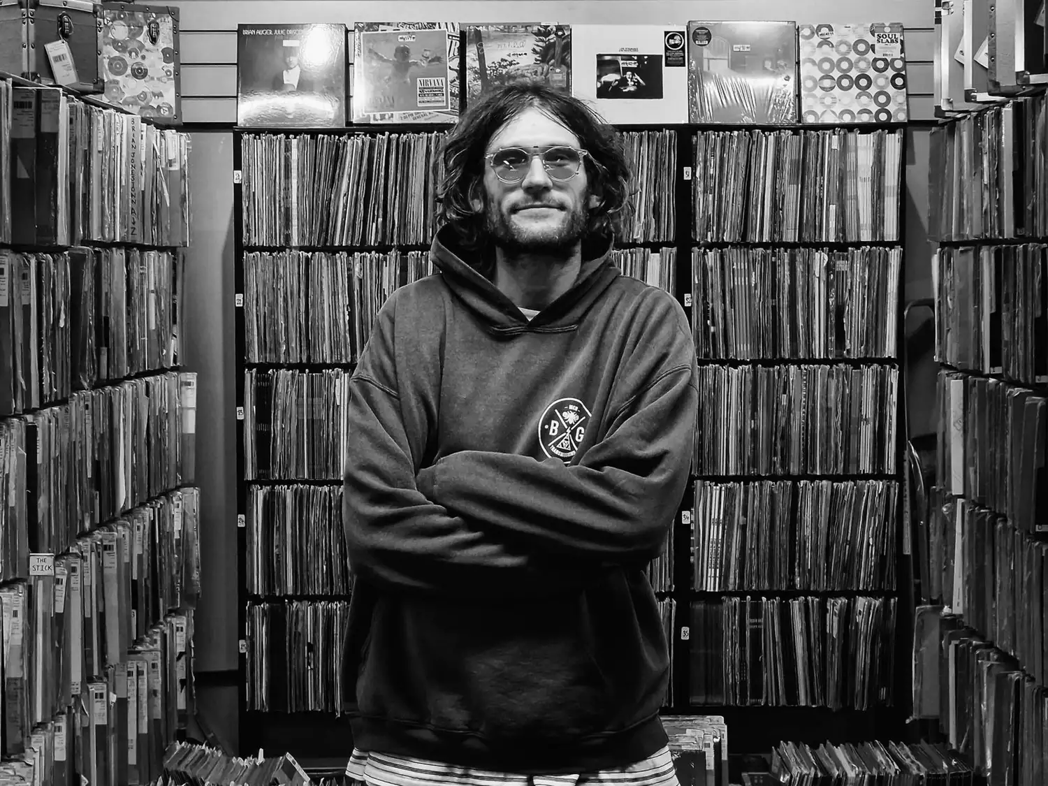 Black and white photo of Matt Ward stood in front of a record collection