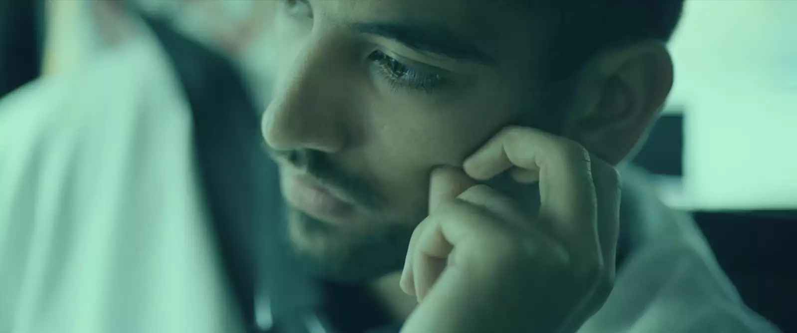 Still from In Camera. Close-up of Nabhaan Rizwan wearing a seatbelt in a car, looking to the side and touching his face.