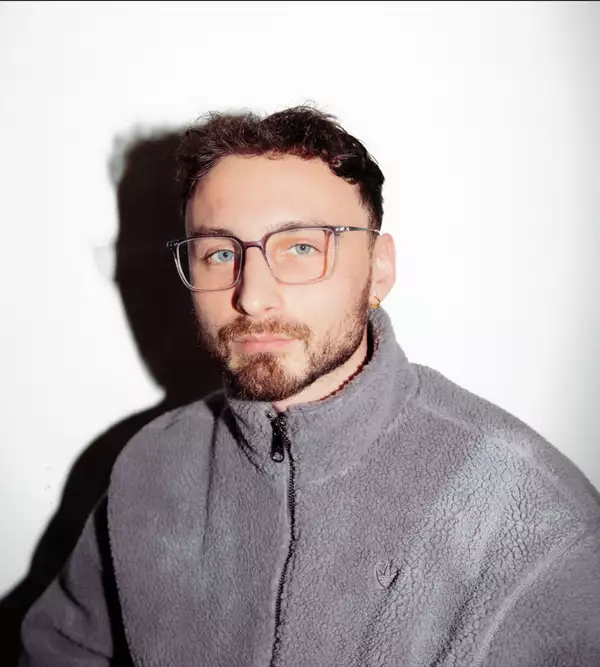 Arif True wearing a fluffy grey adidas fleece on a white background