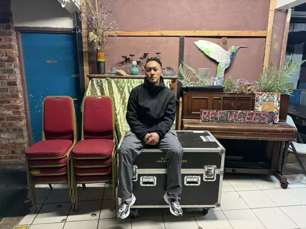 Anton Phung backstage surrounded by stacked chairs, a piano and kit boxes
