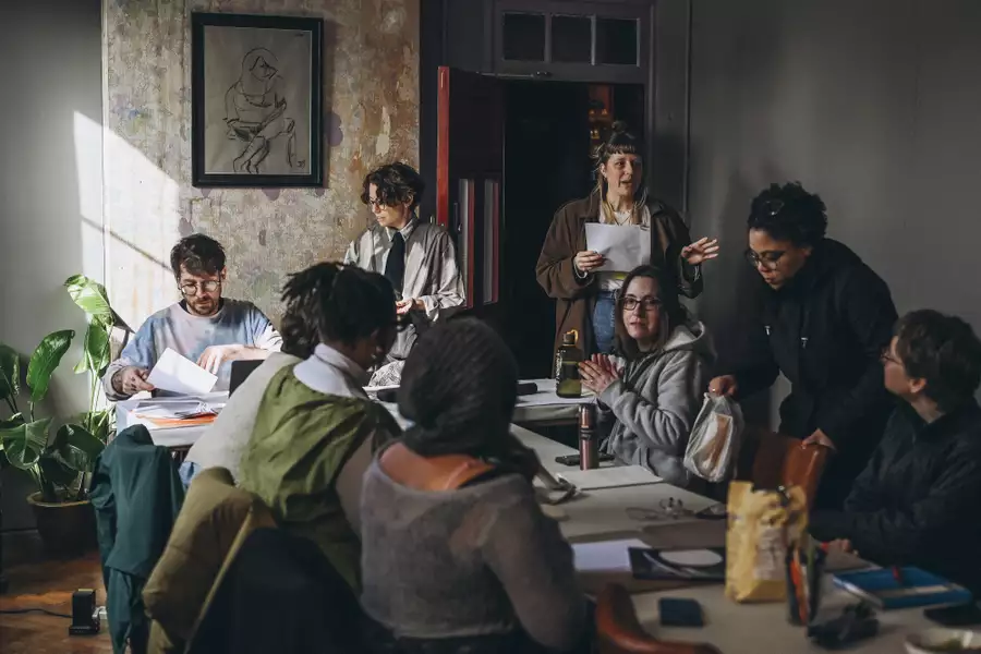 A group of people sat around a table talking with papers and books