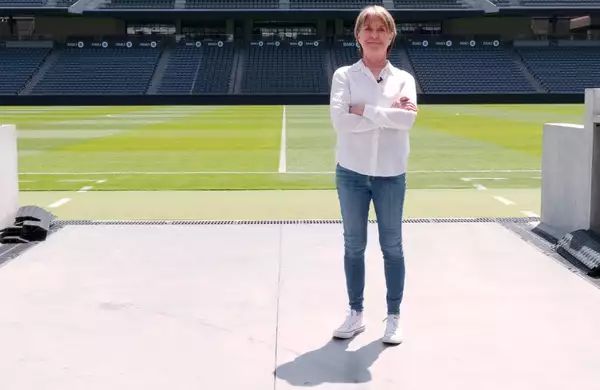 Suzanne Lacy stood on a football pitch wearing a white shirt and blue jeans