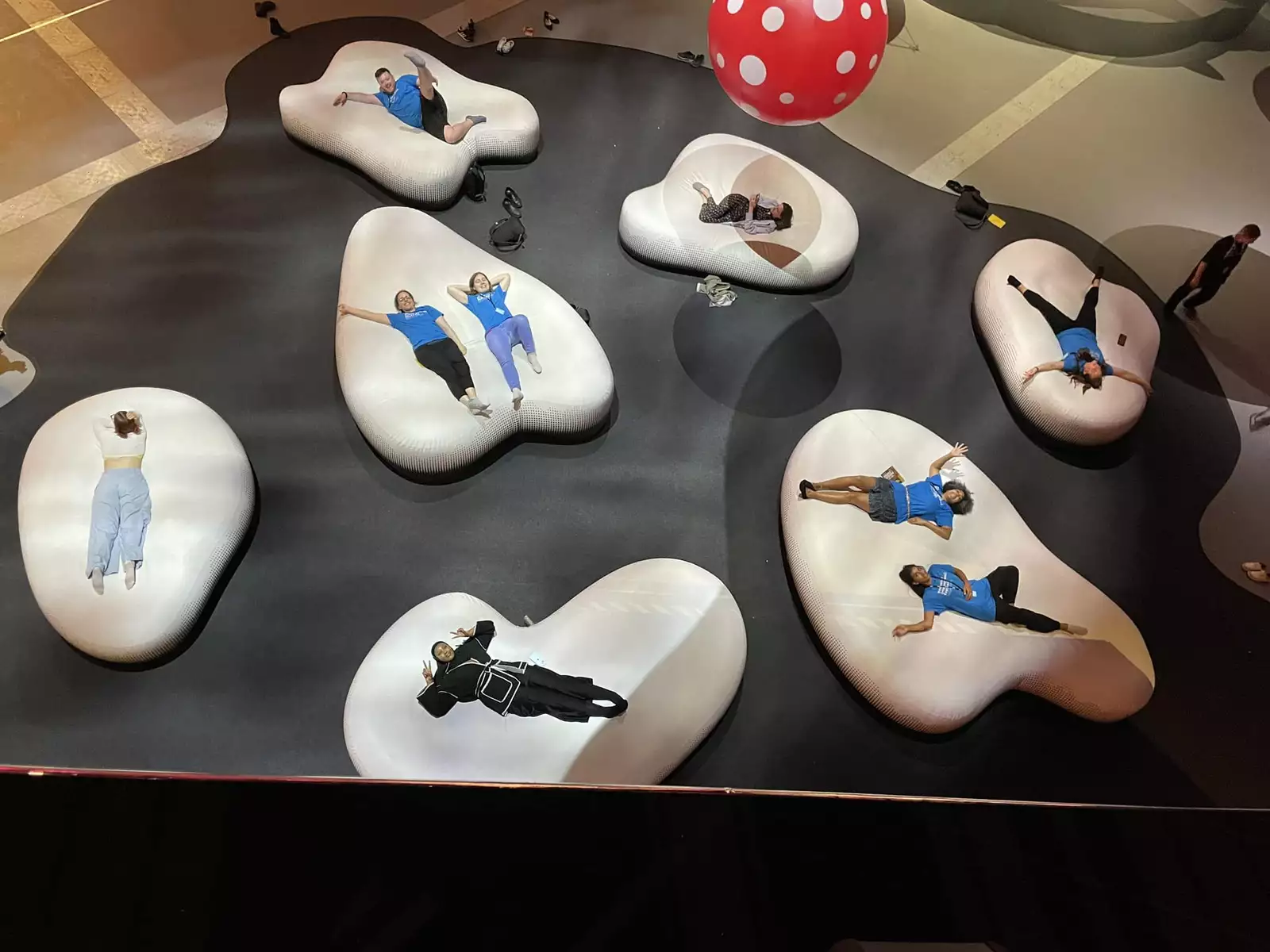 A group of volunteers lying on the cloud installation at the Yayoi Kusama You Me and the Balloons exhibition