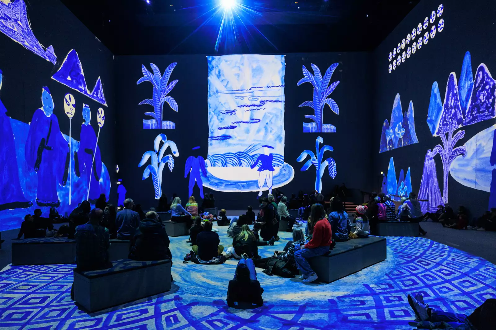 Photograph of David Hockney: Bigger & Closer (not smaller & further away) at Lightroom showing people sitting immersed in blue light and one of Hockney's artworks