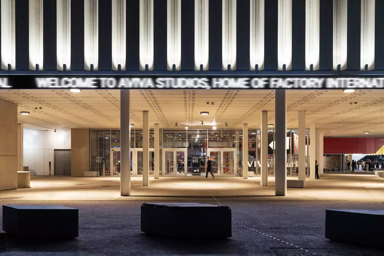 The entrance to Aviva Studios at night with a ticker that reads 'Welcome to Aviva Studios, home of Factory International'