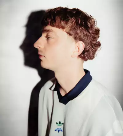 Brody Salmon turned to the side, wearing a white Adidas jumper with a black collar, on a white background