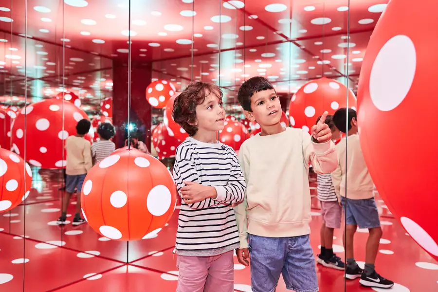 Two children enjoy a red and white polka dot installation by Yayoi Kusama