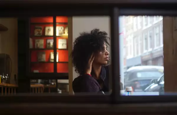 Juliet Ellis inside a dark bar, looking out the window at the street outside.