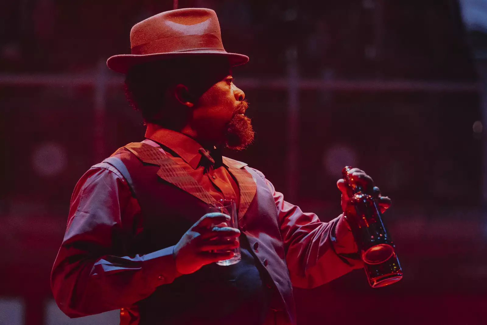 A person acting on stage during Liberation at Royal Exchange Theatre. The lighting is red.