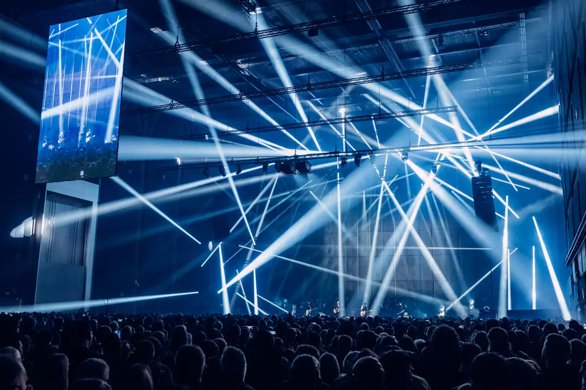 A blue laser display in the Warehouse during the Johnny Marr Orchestra. There is a huge crowd of people watching the performers.