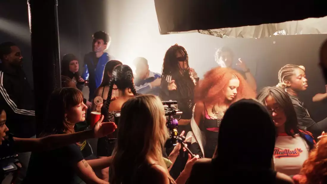 A still from the 'Meet the cohort' video showing a crowded room of people chatting with cameras