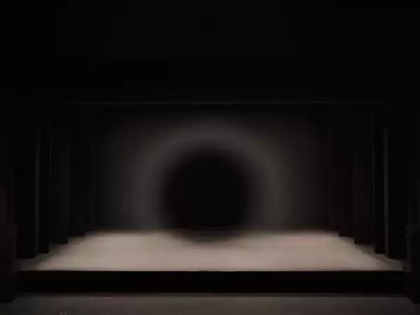 Photo of a large circle dim light on stage during A Possibility