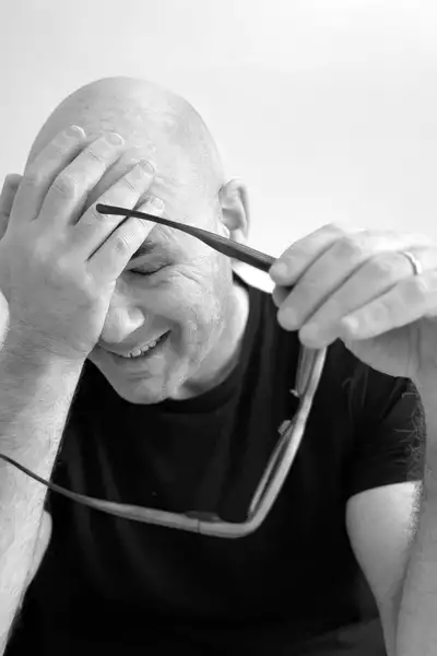 Black and white headshot of Yaron Lifschitz holding his glasses and touching his eyes
