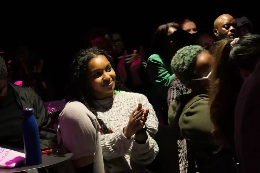 A person clapping and smiling in the audience. They are looking off-centre to the side.