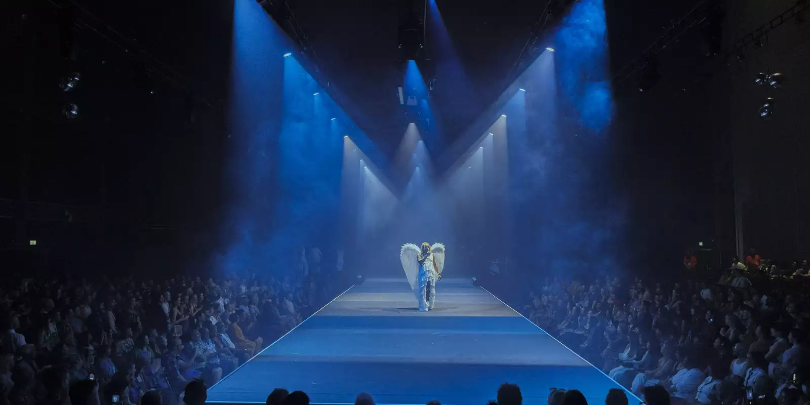 A performer on the runway with a huge crowd in the Warehouse during House of MCR