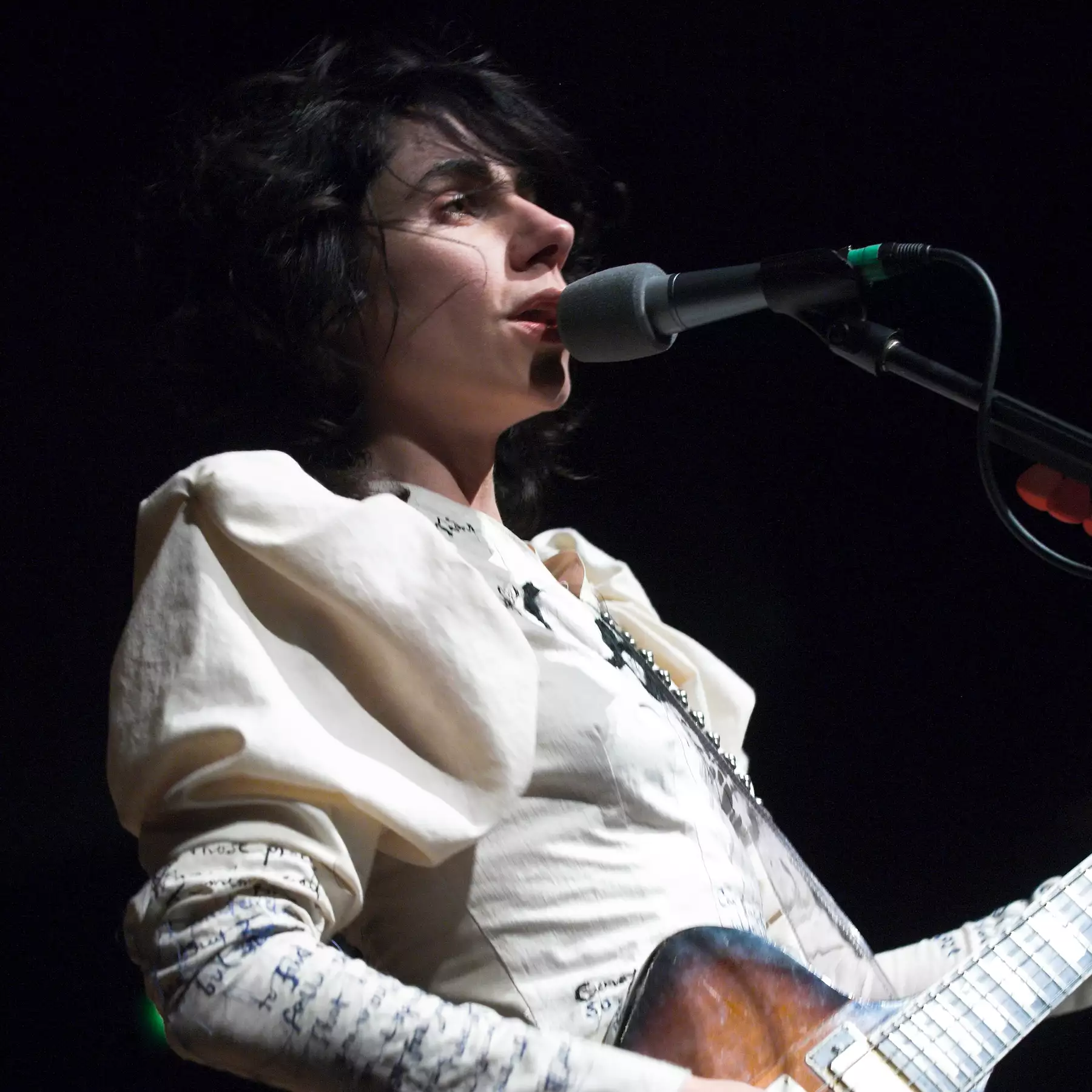 PJ Harvey wearing white and playing guitar
