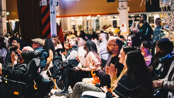 Large group of people smiling and clapping in the Social.