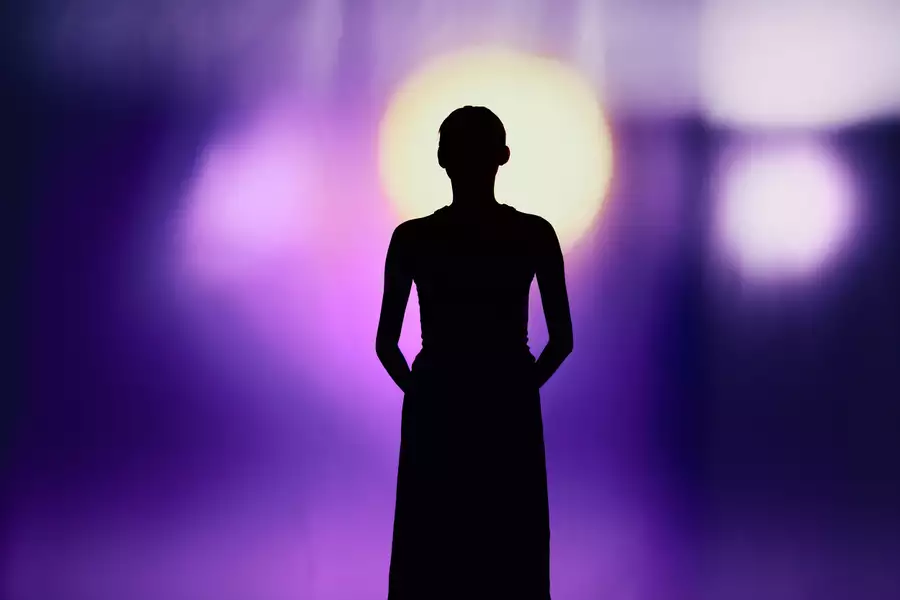 A silhouette of a person against a background with bright purple light