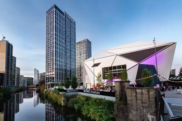 Aviva Studios on a sunny day next to skyscrapers