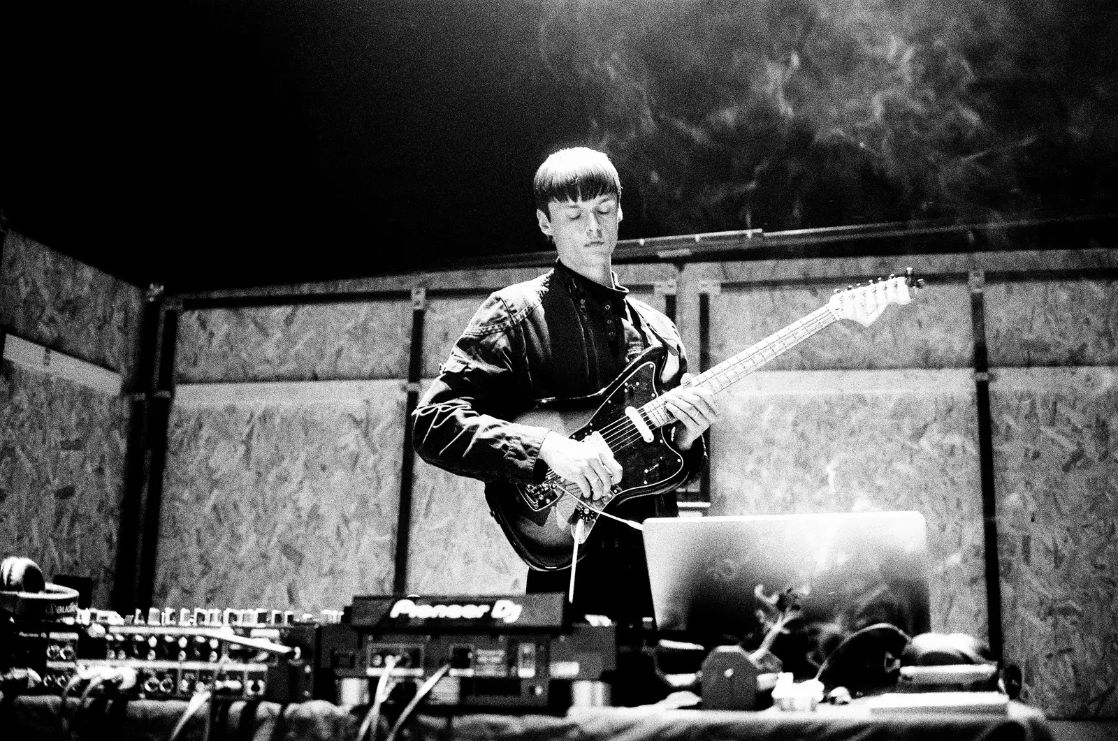 Black and white photograph of a member of 54: Manchester playing guitar inside their installation