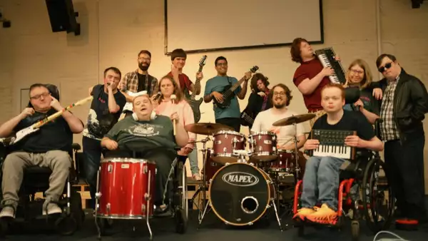 A large group of people in a hall holding up instruments and smiling