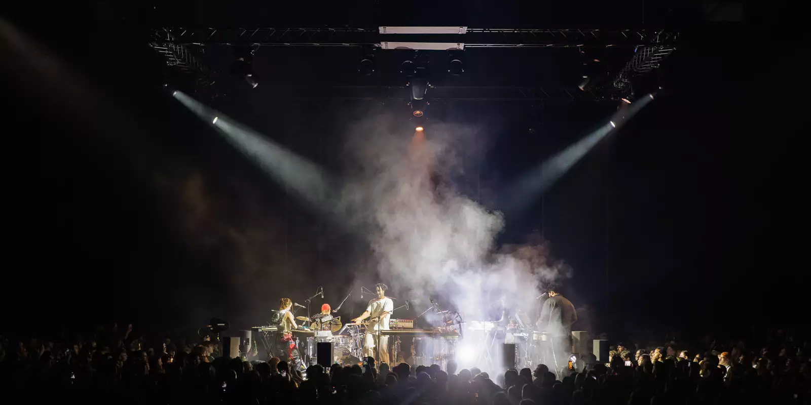 Band on stage with fog and spotlights and silhouettes of crowd