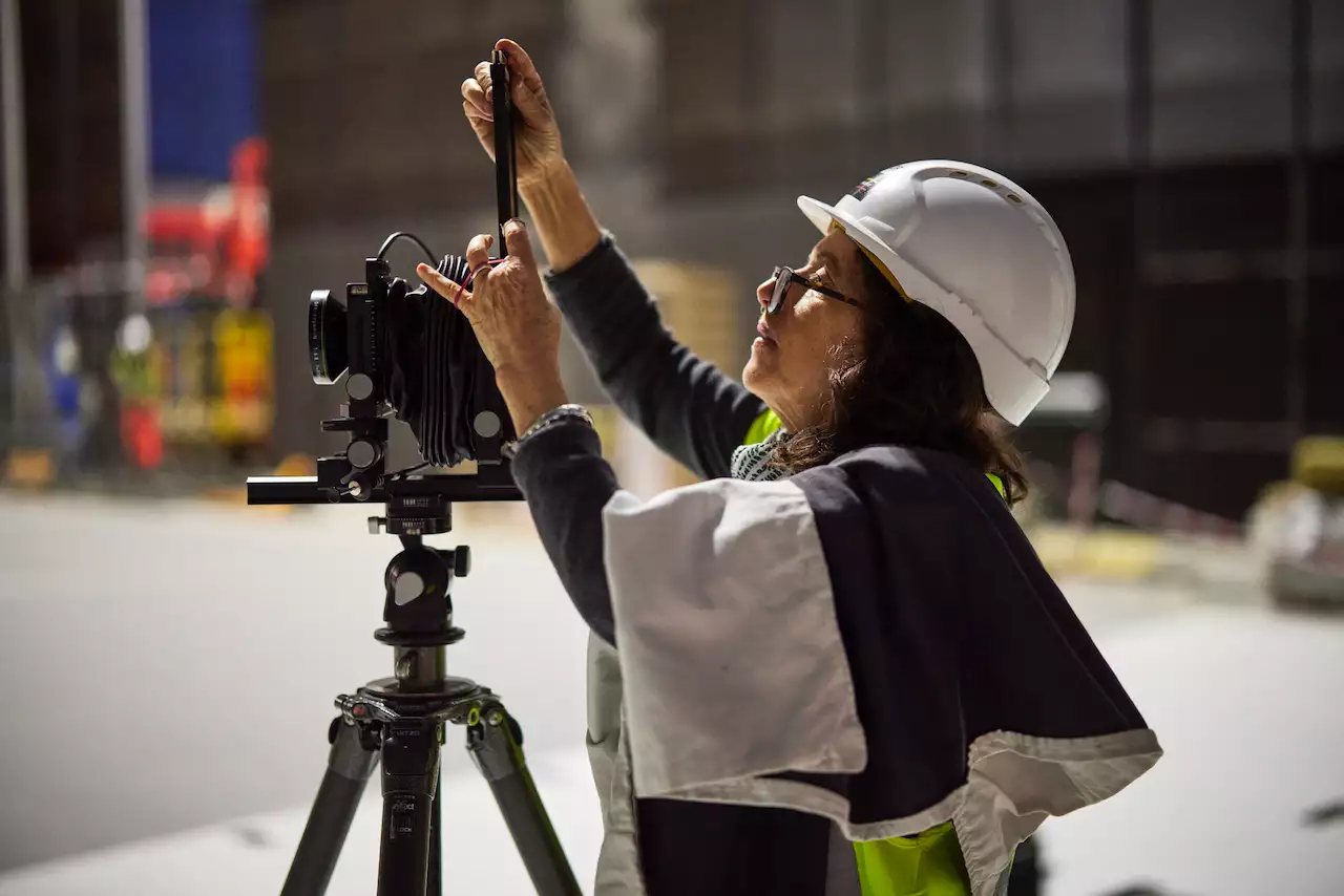 Hélène Binet wearing a hard hat and adjusting a camera