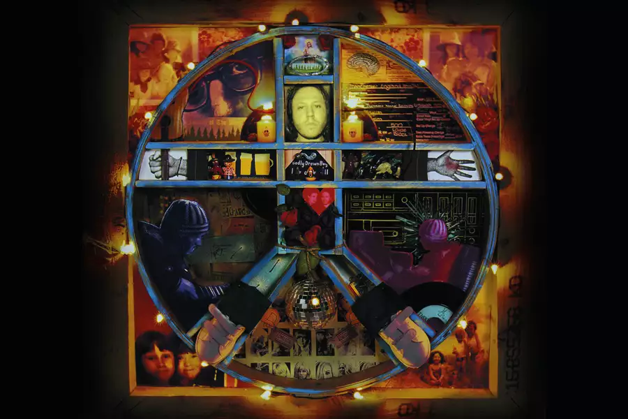 This image shows the album cover for The Hour of Bewilderbeast by Badly Drawn Boy. The cover features a circular collage of various images, photographs, and abstract designs arranged within a segmented circle. The collage includes a portrait of a person, hand-drawn elements, hands, flowers, and objects like a disco ball. The color scheme is a mix of deep reds, blues, and yellows, giving the design a warm, nostalgic, and eclectic feel. Lights surround the outer edge of the circle, adding a glowing effect.