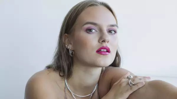 Close up headshot of Grete wearing bright pink lipstick and purple eyeshadow