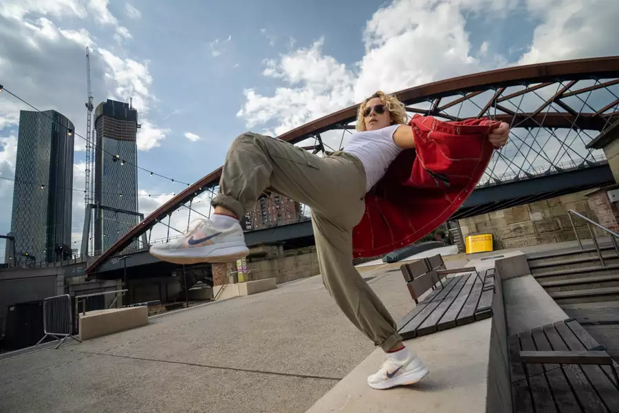 A person posing on a bench outside Aviva Studios wearing sunglasses