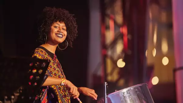 Photo of Zola Tec smiling and playing the steel drum on stage