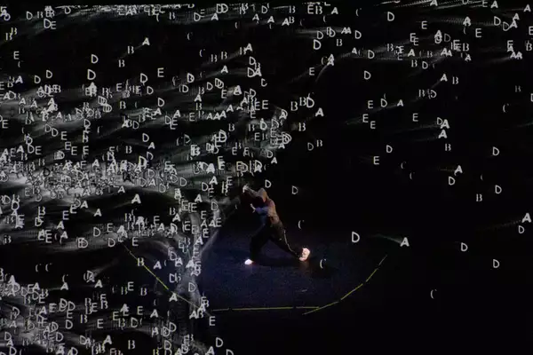 Chad Taylor dancing on stage with lettering on a screen behind him