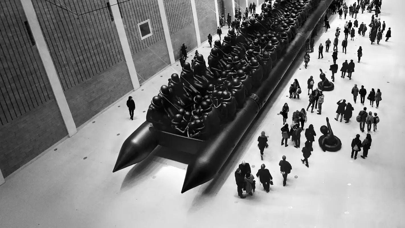 Ai Weiwei's Law of the Journey artwork, showing a crowd of people surrounding a huge, inflatable migrant boat in a big warehouse