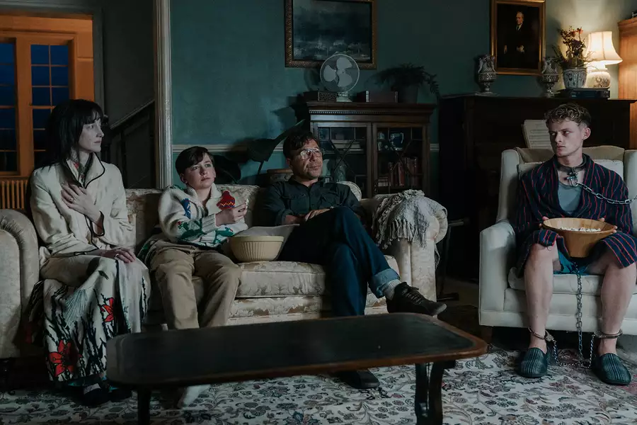 Still from The Good Boy showing a family sat on a sofa in a living room, with one man in chains