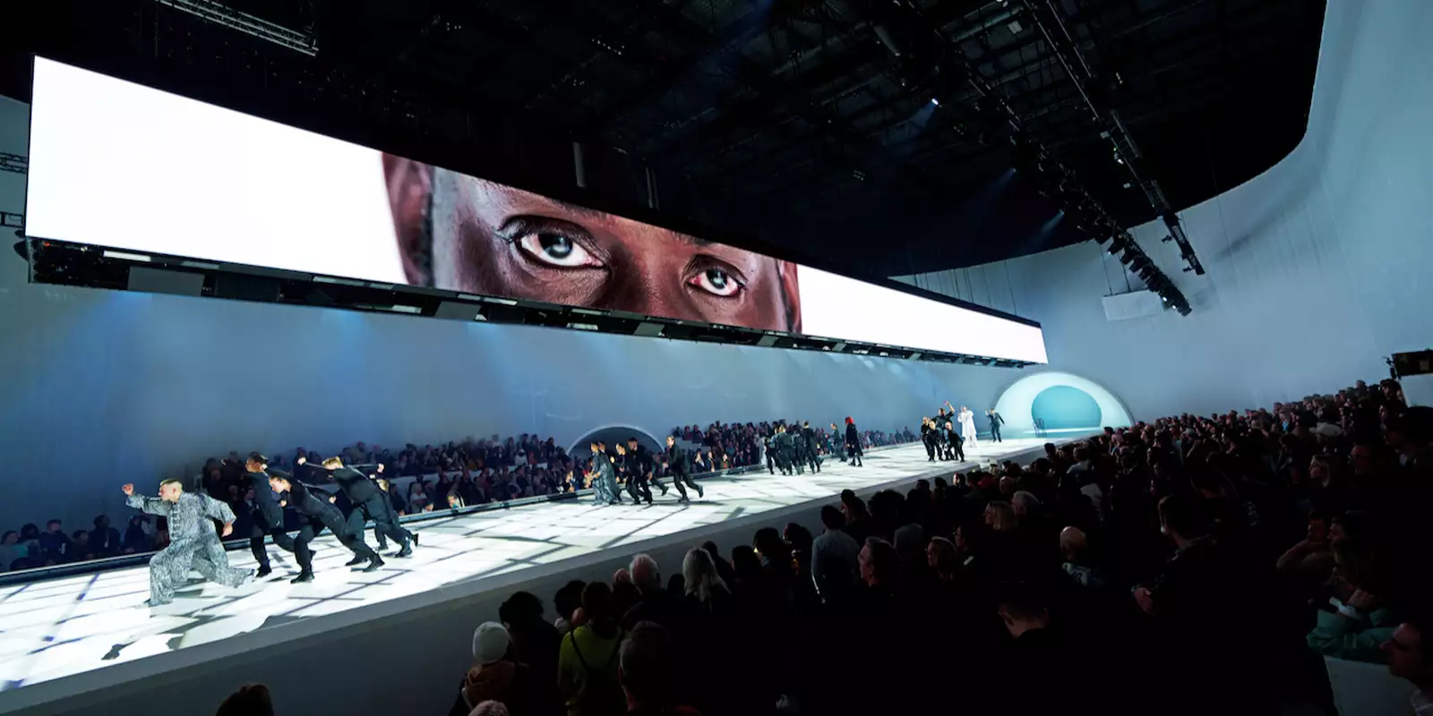 Dancers performing under a screen showing a person's eyes in Free Your Mind