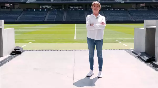 Suzanne Lacy stood on a football pitch wearing a white shirt and blue jeans
