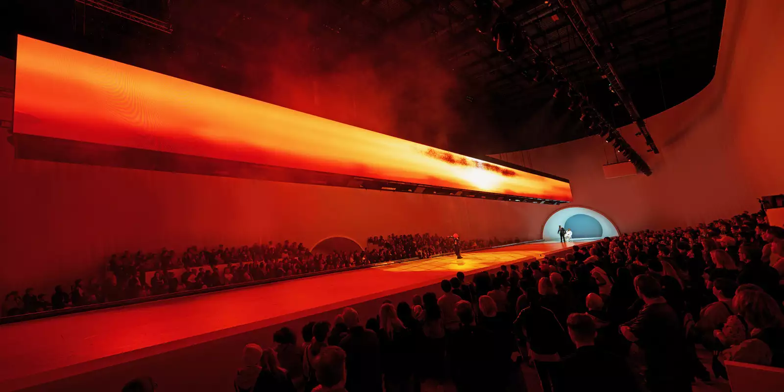 A crowd watching a dancer on stage during Free Your Mind in the Warehouse. The lighting is red.