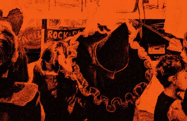 An orange photo of children watching a performance. One is wearing a witch fancy dress hat.