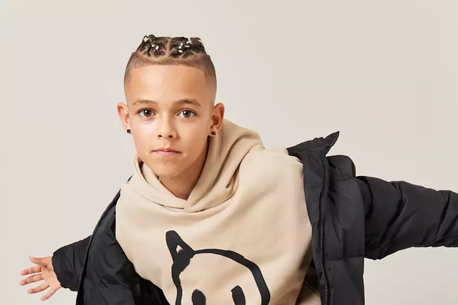 Trey Braine wearing a beige hoodie and black coat, dancing