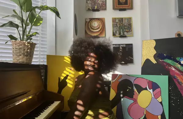 Misha B with paintings and a piano