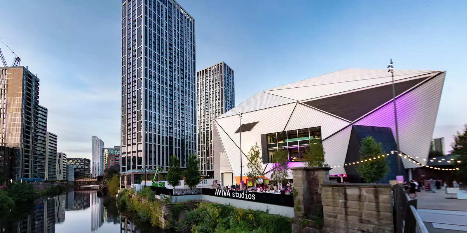 Aviva Studios on a sunny day next to skyscrapers