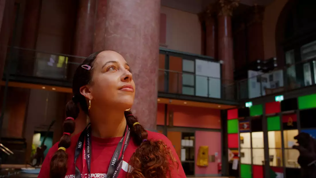 Still from film showing Stephanie Reynolds looking at the ceiling in the Royal Exchange