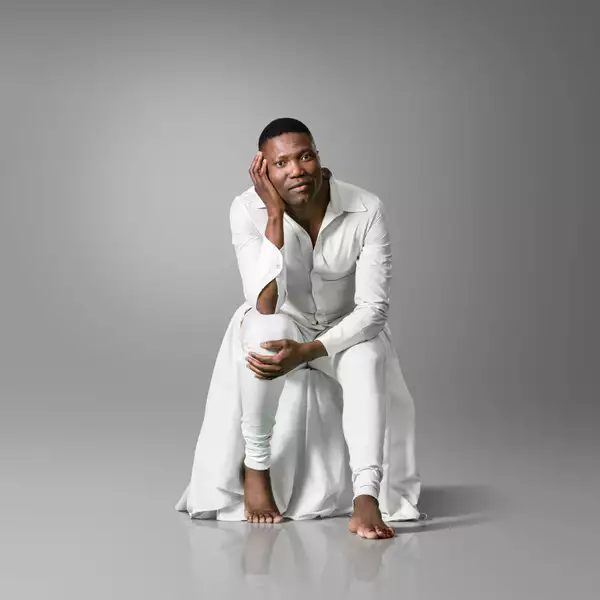 Gregory Maqoma wearing all white clothing on a grey background