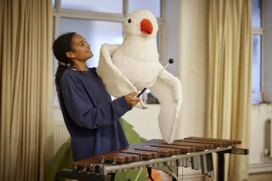 A puppeteer holding a seagull puppet and playing the xylophone